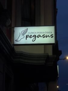 Se muestra el cartel luminioso del exterior de la clínica podológica Pegasus.