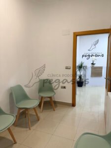 Se muestra la sala de espera de la clínica podológica Pegasus con la entrada al fondo.